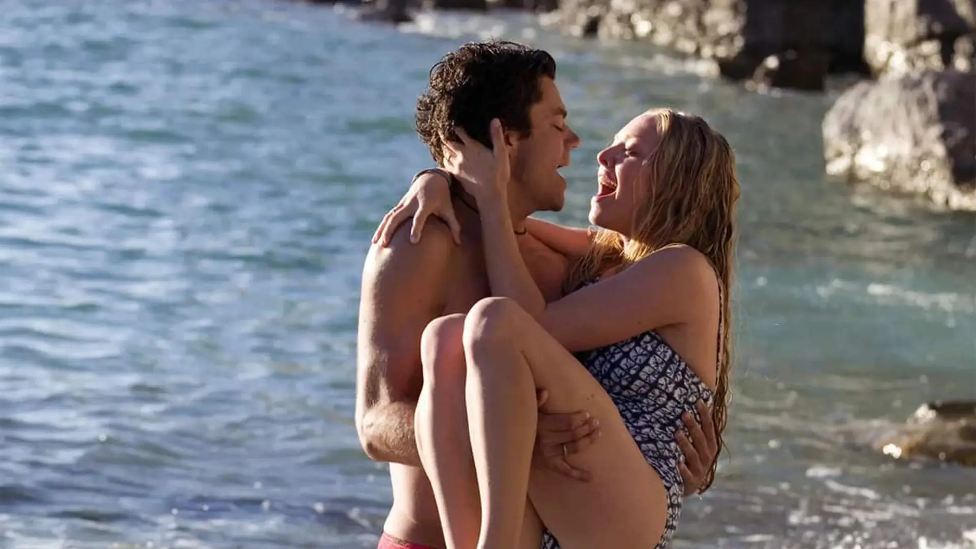 Pareja abrazándose en la orilla del mar en una escena romántica ambientada en verano.