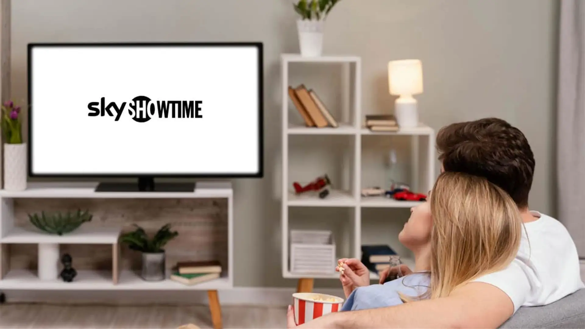 Pareja relajada en el sofá disfrutando de contenidos en la televisión con el logo de SkyShowtime.