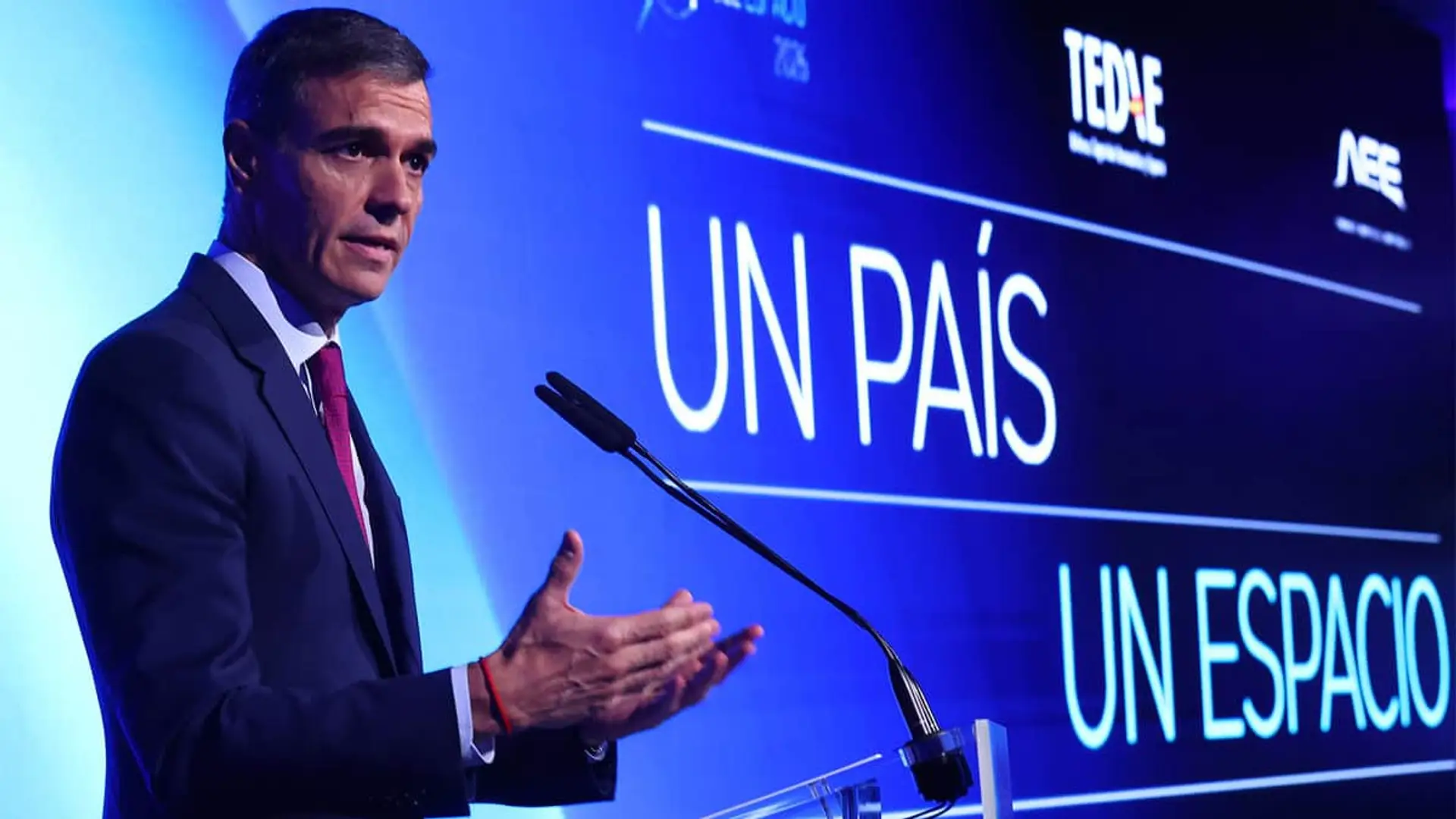 Pedro Sánchez, presidente del Gobierno, en un discurso con el lema Un país, un espacio y logos de TEDAE y AEE.