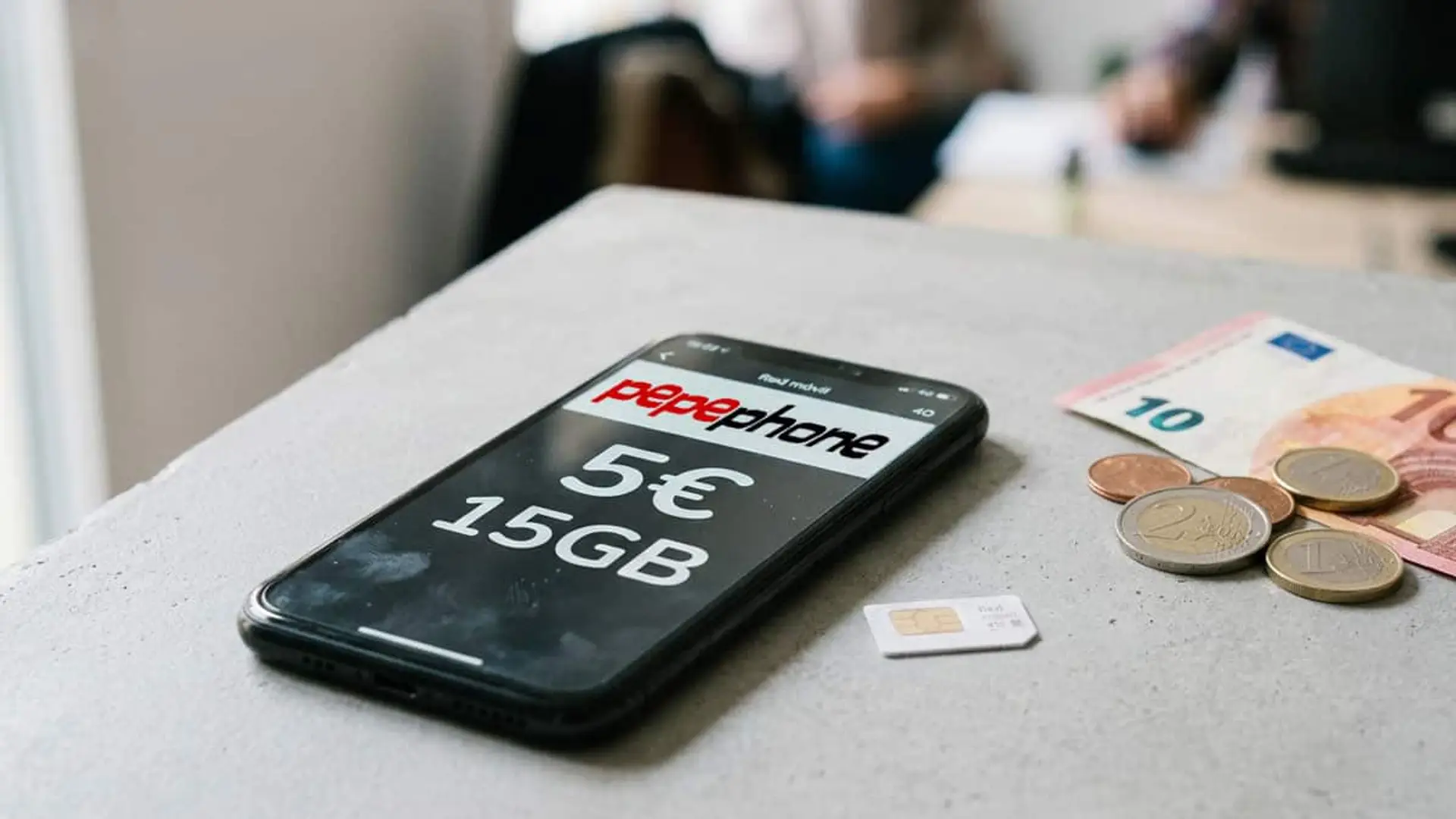 Móvil con tarifa de Pepephone de 5 euros y 15 GB junto a una tarjeta SIM y dinero