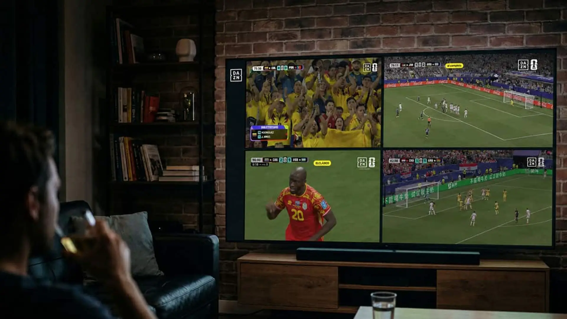 Persona viendo una pantalla con cuatro partidos de fútbol en DAZN desde el salón de casa