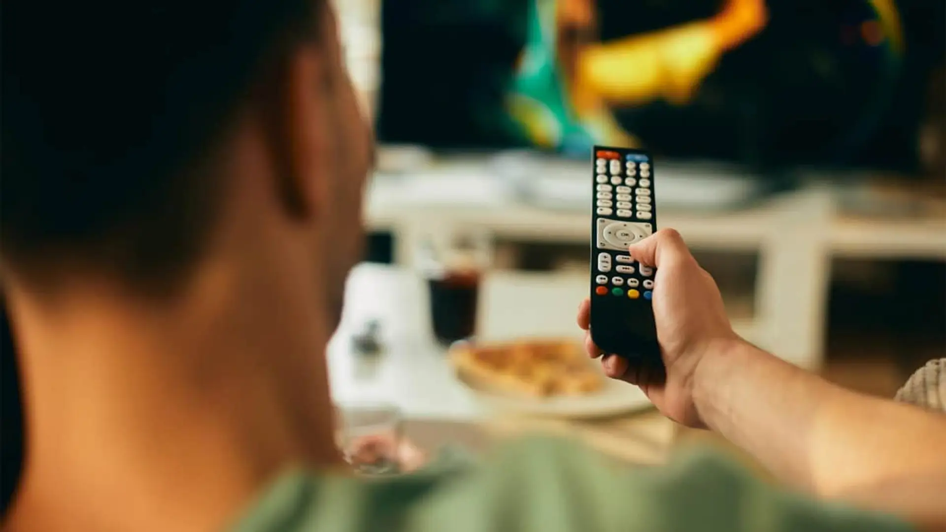 La revolución de la TDT sigue: habrá un nuevo canal autonómico Persona usa el mando a distancia para elegir una película o serie en la TV.