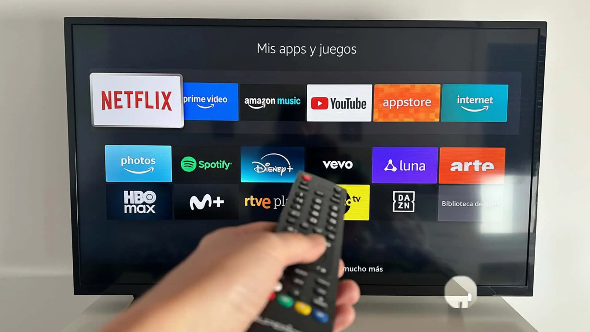 Interfaz de una Smart TV con su menú de apps: Netflix, Prime Video, Disney+ y HBO Max. Una mano navega con el mando a distancia.