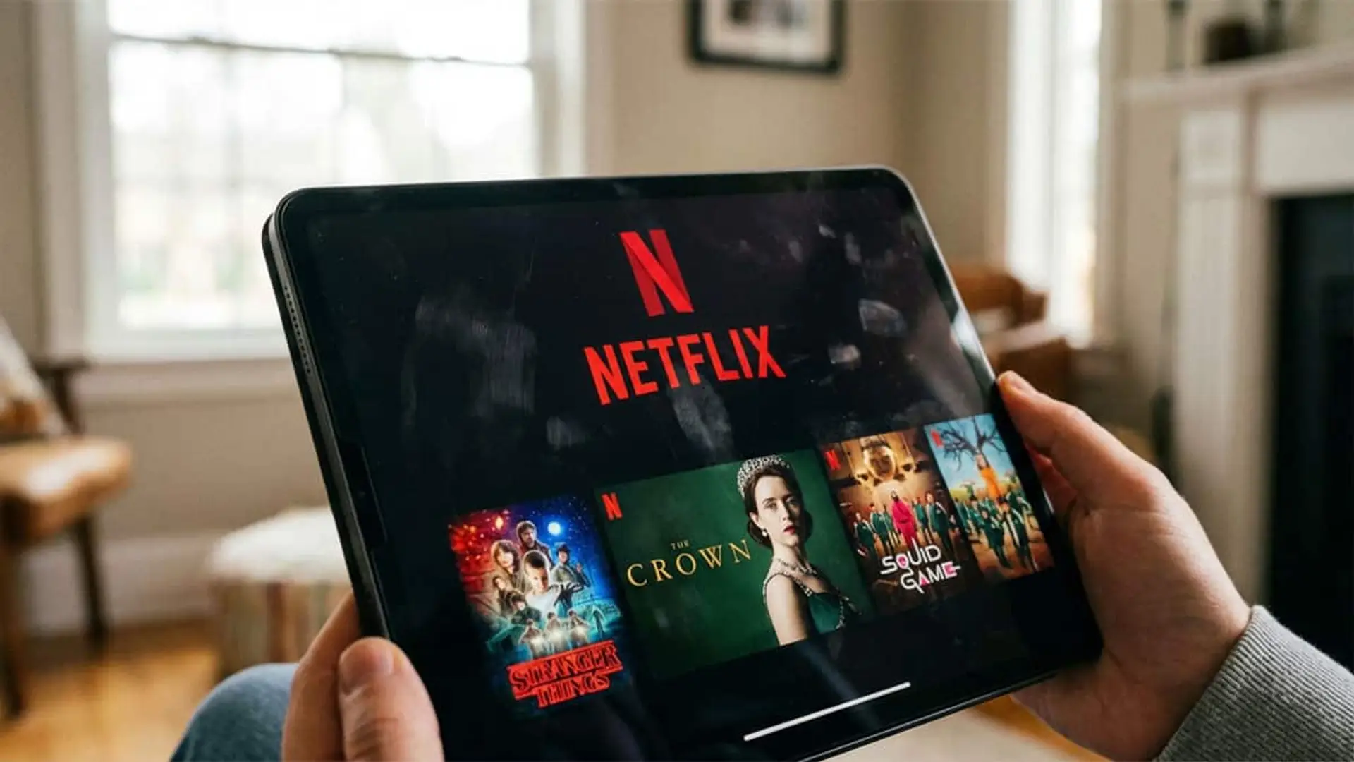Persona sujetando una tablet con la plataforma Netflix abierta y varias series destacadas en pantalla.