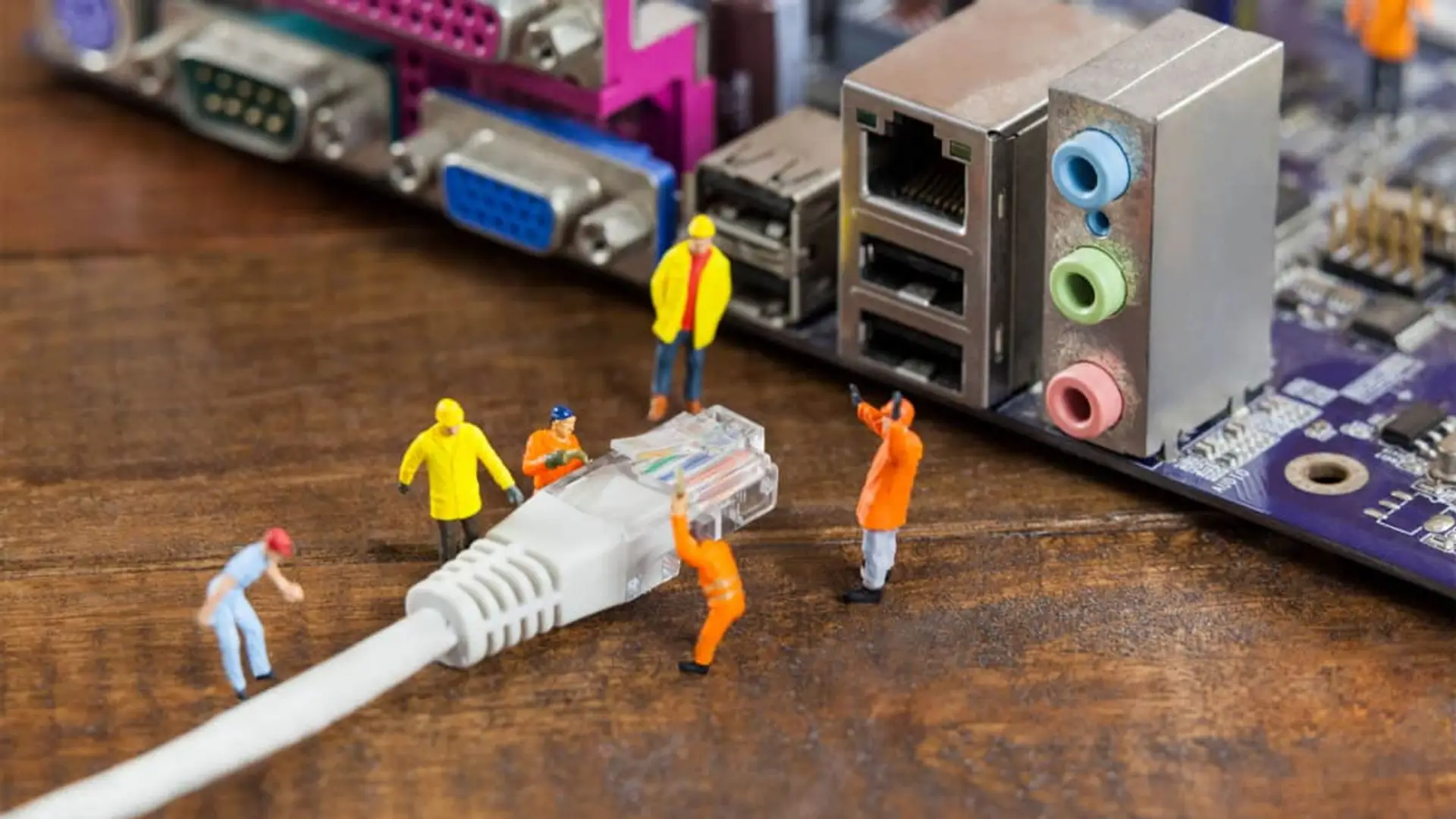 Figuras en miniatura de técnicos trabajando en la conexión de un cable de red Ethernet para representar el servicio técnico.