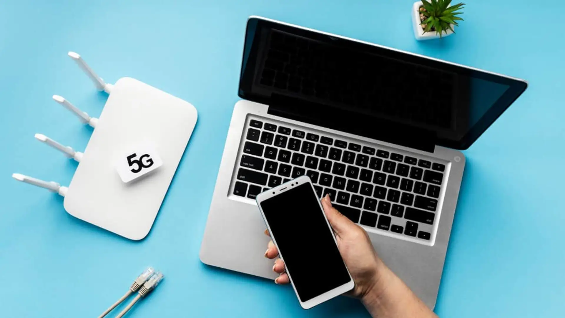Router WiFi 5G blanco junto a portátil y smartphone para conexión a internet de alta velocidad.
