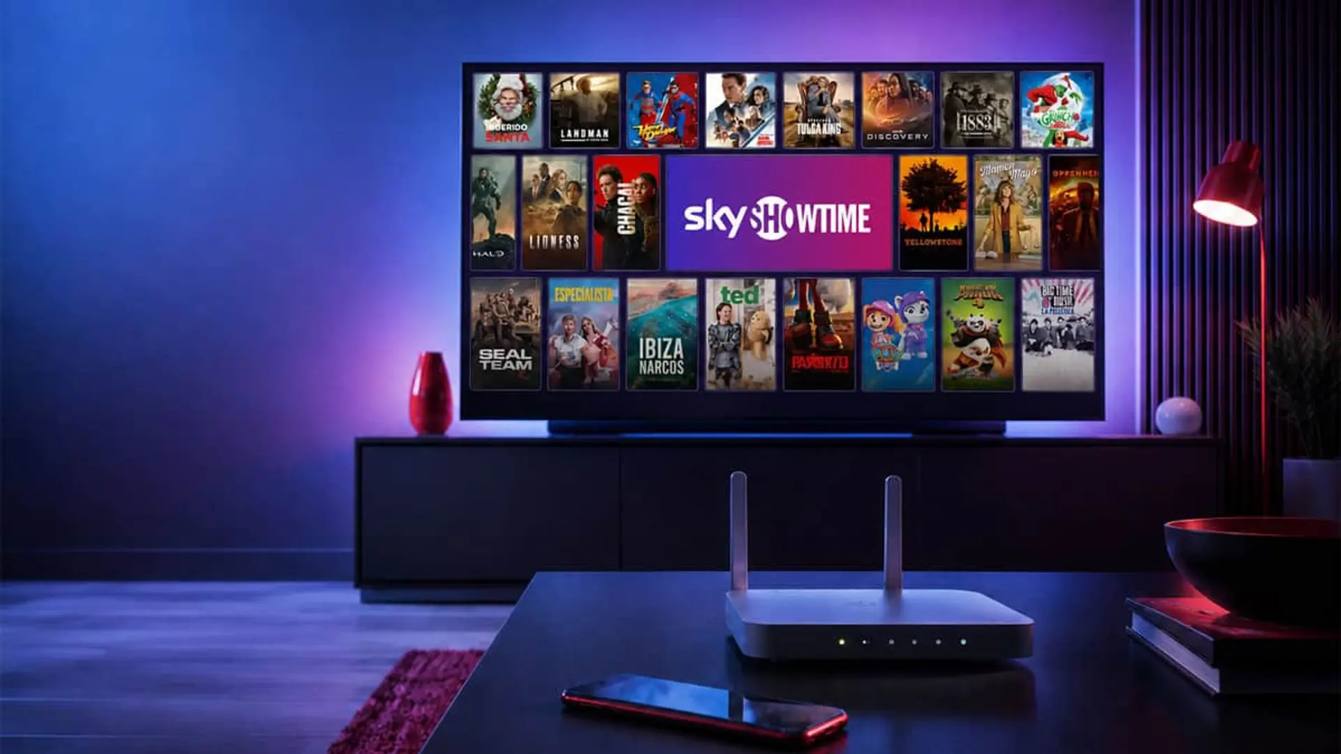 La tarifa low cost con SkyShowtime que ni Digi ni O2 ofrecen Televisor con SkyShowtime, router wifi y móvil en un salón moderno con iluminación azul y violeta.