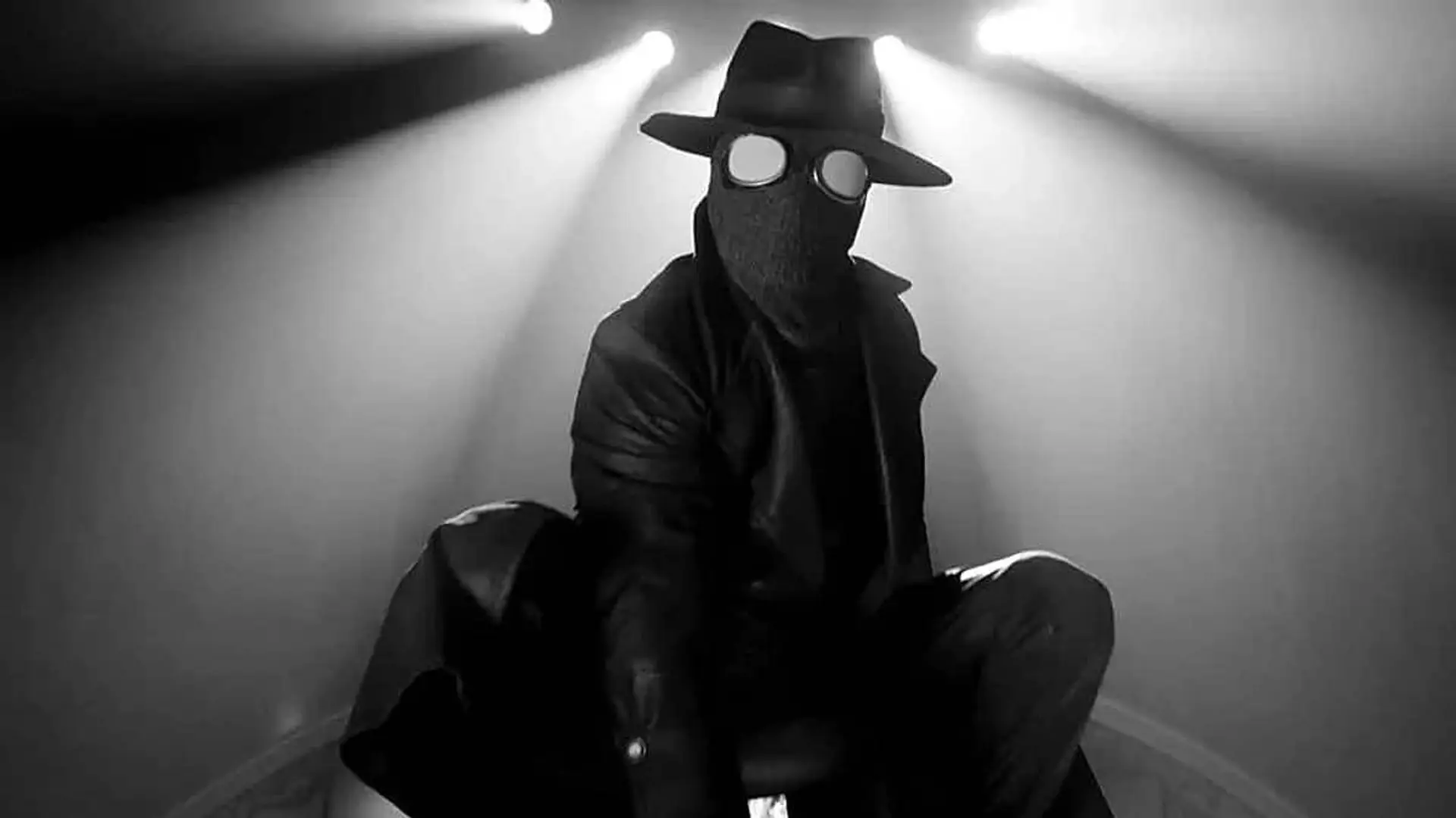 Spider-Noir con traje negro, sombrero y gafas bajo varios focos
