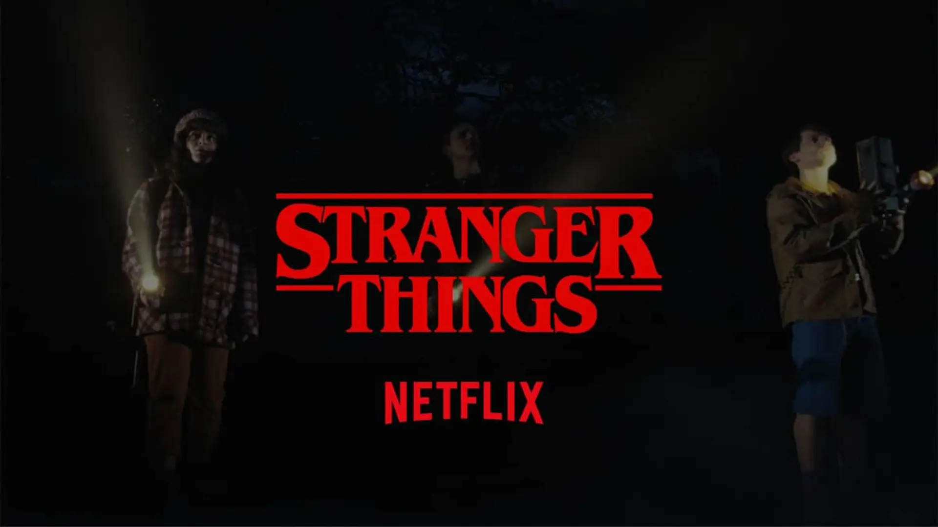 Logo de la serie Stranger Things de Netflix con personajes usando linternas en un bosque oscuro.