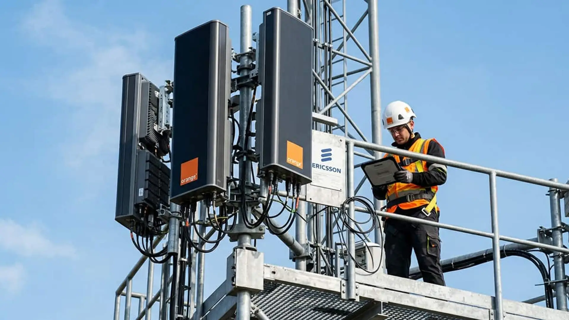 Técnico trabajando junto a antenas de Orange y equipos de Ericsson en una torre de telecomunicaciones