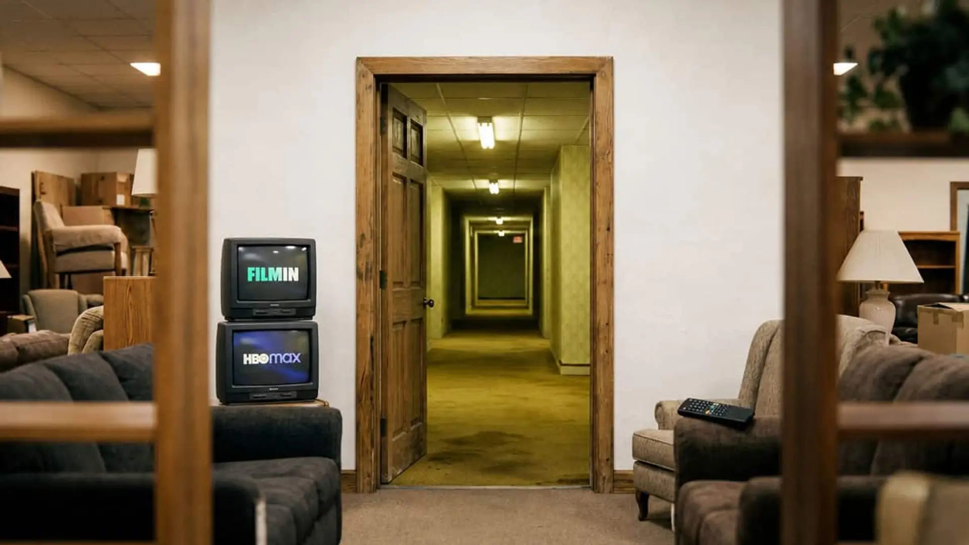 Dos televisores apilados con Filmin y HBO Max junto a la entrada de un largo pasillo con sillones a ambos lados