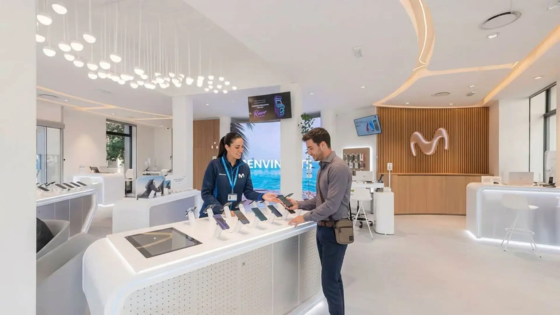 Experta asesorando a un cliente en una tienda moderna de Movistar con varios smartphones en exposición para su venta.
