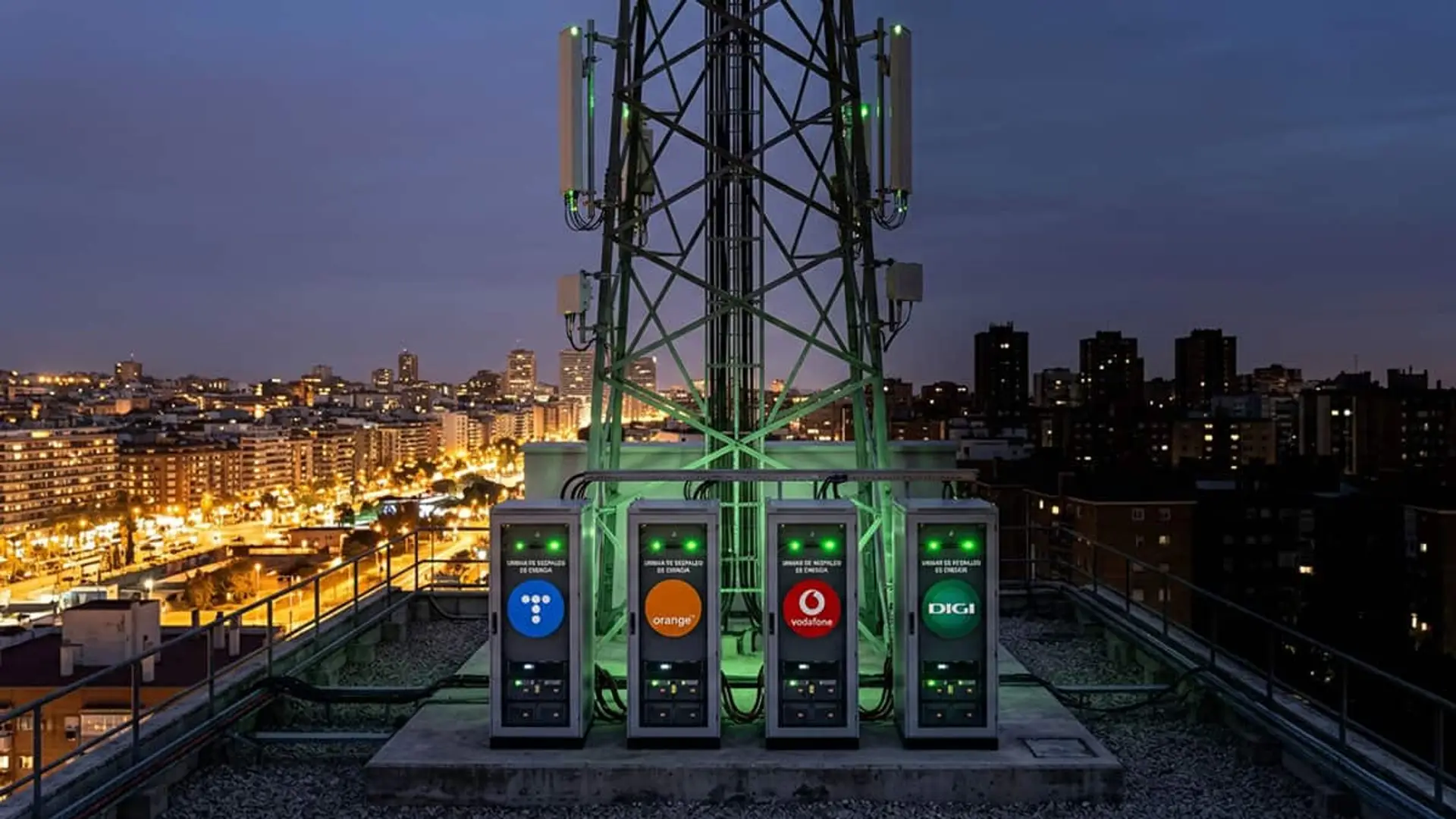 Torre de telecomunicaciones en una azotea con baterías de respaldo de Telefónica, Orange, Vodafone y DIGI al anochecer