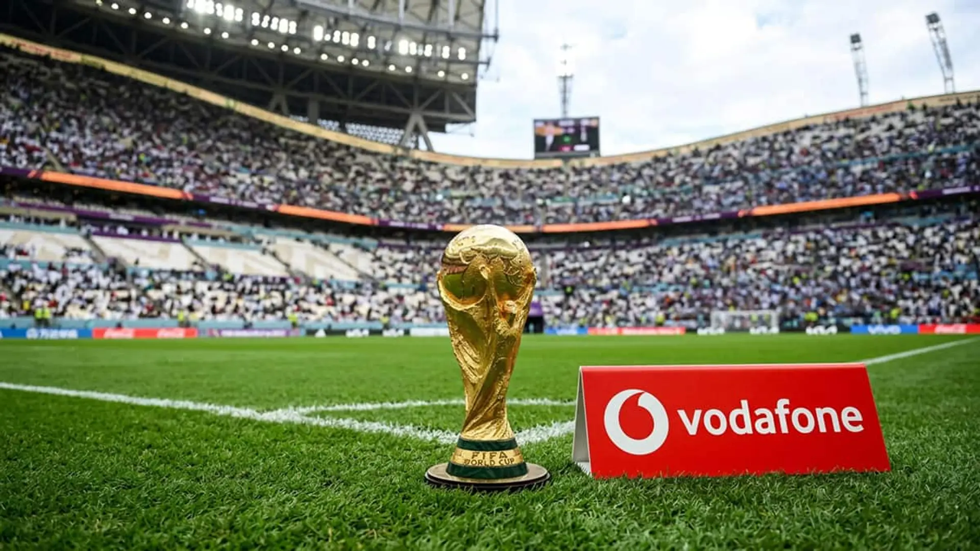 Trofeo de la Copa Mundial de la FIFA sobre el césped de un estadio junto a un cartel de Vodafone