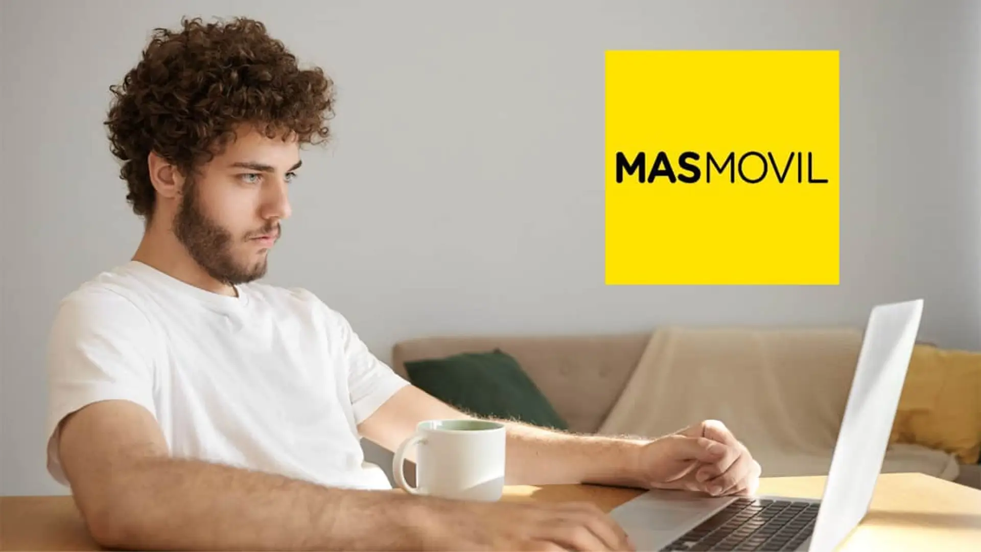 Joven con pelo rizado trabajando desde casa con su portátil. Logotipo de la compañía de fibra y móvil MASMOVIL.