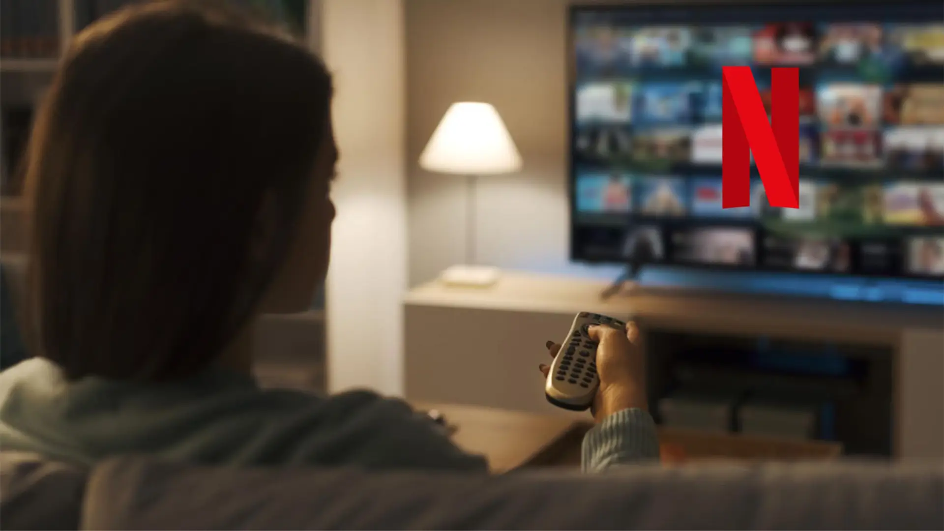 Netflix limpia su catálogo de Originales en 2026: estas son las series y películas que desaparecen Mujer navegando por el catálogo de Netflix en su Smart TV con el mando a distancia desde el sofá.