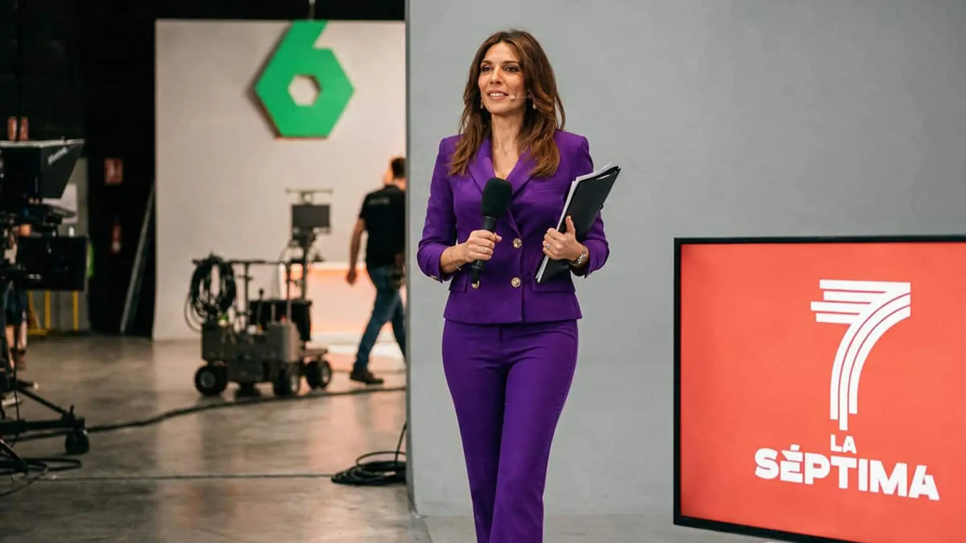 La presentadora Verónica Sanz con traje morado y micrófono en un plató de La Sexta junto al logotipo de La Séptima