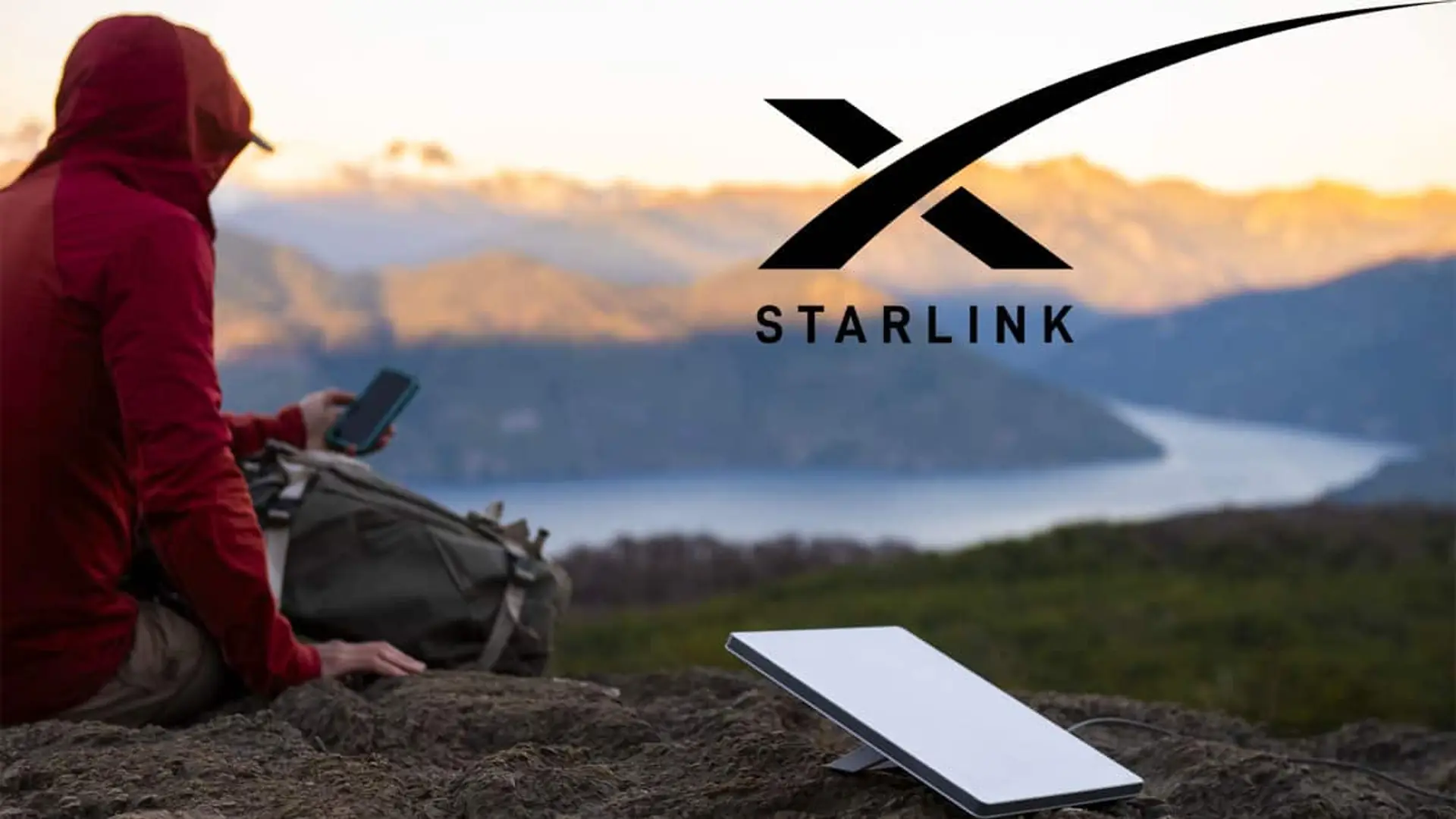 Viajero con mochila usando conexión satelital Starlink en una zona remota con montañas al fondo.