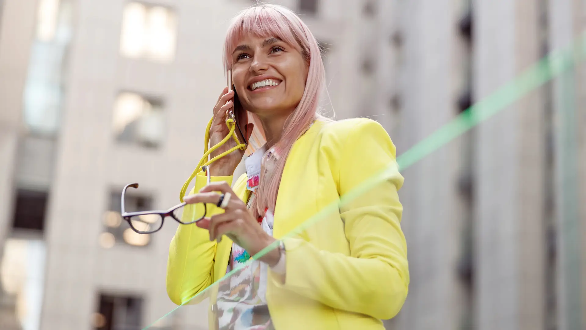 Mujer con pelo rosa y chaqueta neón escucha sonriente sus mensajes de voz de su móvil adamo Mujer con pelo rosa y chaqueta neón escucha sonriente sus mensajes de voz de su móvil adamo