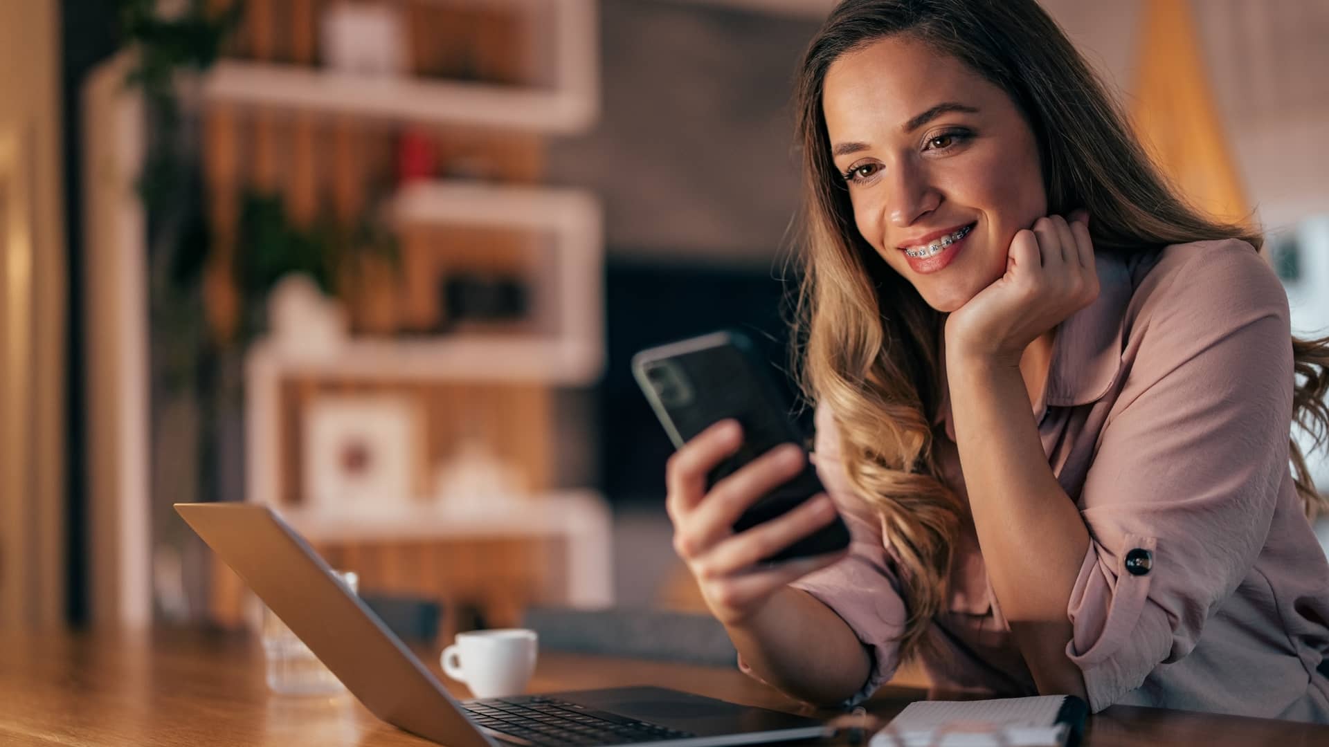 Joven con aparato mira sonriente en su móvil las tarifas de Avatel