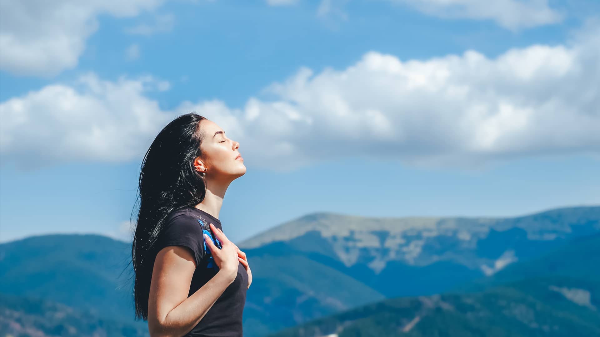Mujer joven respira profundamente en la cumbre de una montaña representando la paz que aportan las tarifas sin permanencia