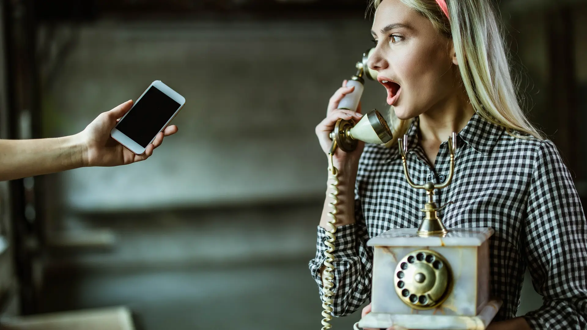 Joven con teléfono fijo sorprendida cuando la ofrecen un móvil simboliza como quitar teléfono fijo Joven con teléfono fijo sorprendida cuando la ofrecen un móvil simboliza como quitar teléfono fijo