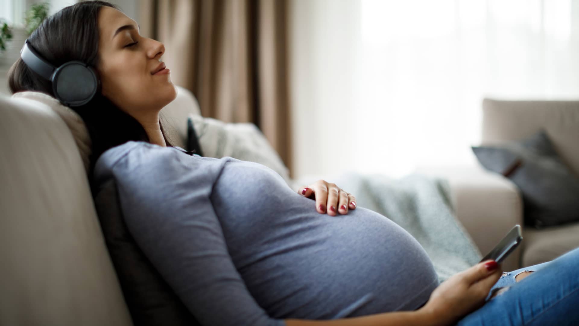 Mujer embarazada escuchando música con su móvil simboliza líneas adicionales