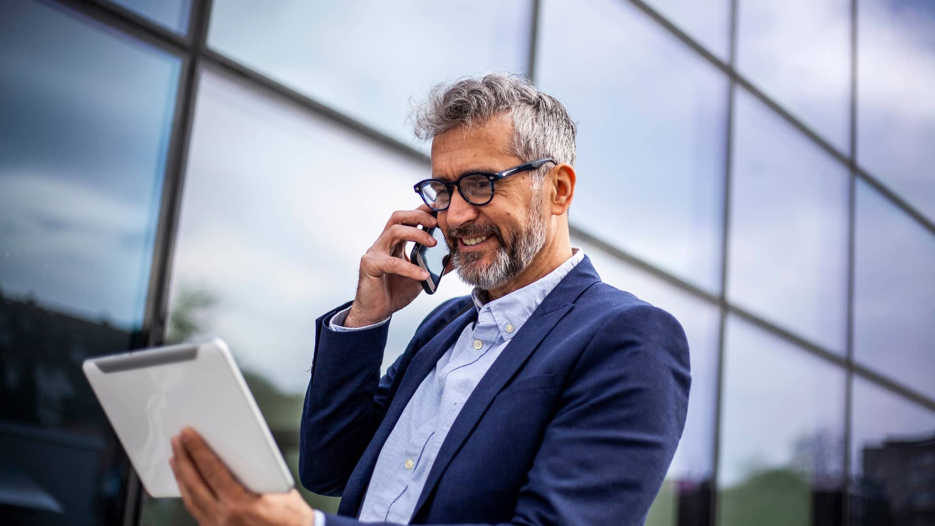 Empresario realizando llamada telefónica mientras observa tablet simboliza llamadas ilimitadas