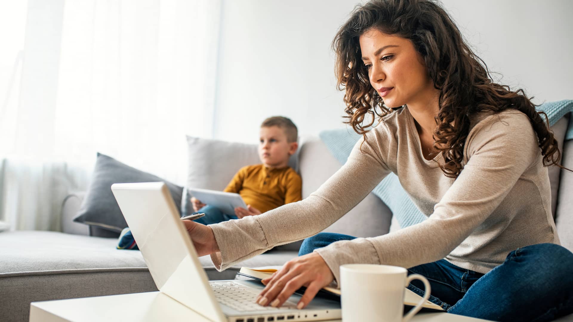 madre e hijo en el sofa de casa utilizando dispositivos electronicos grcas a las nuevas tarifa de internet y movil de cablemovil