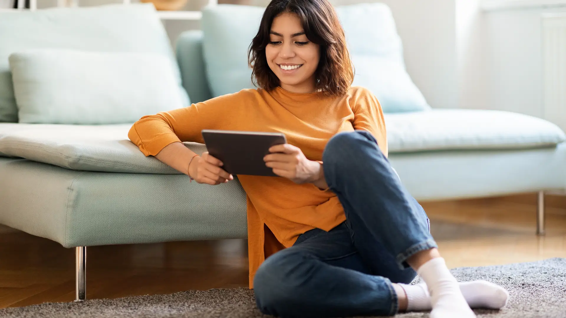 Una joven en el sofá de su casa con la tablet disfrutando de las tarifas de internet de Cleverea