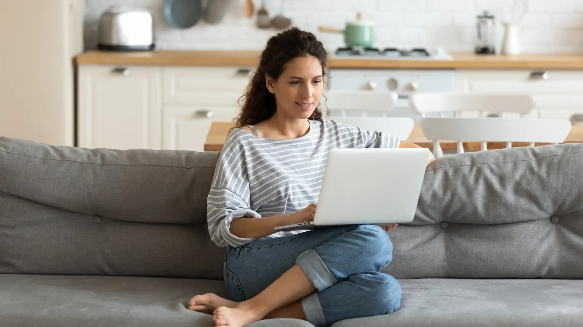 Mujer con el ordenador en el sofá de su casa revisando las tarifas de la compañia Cleverea