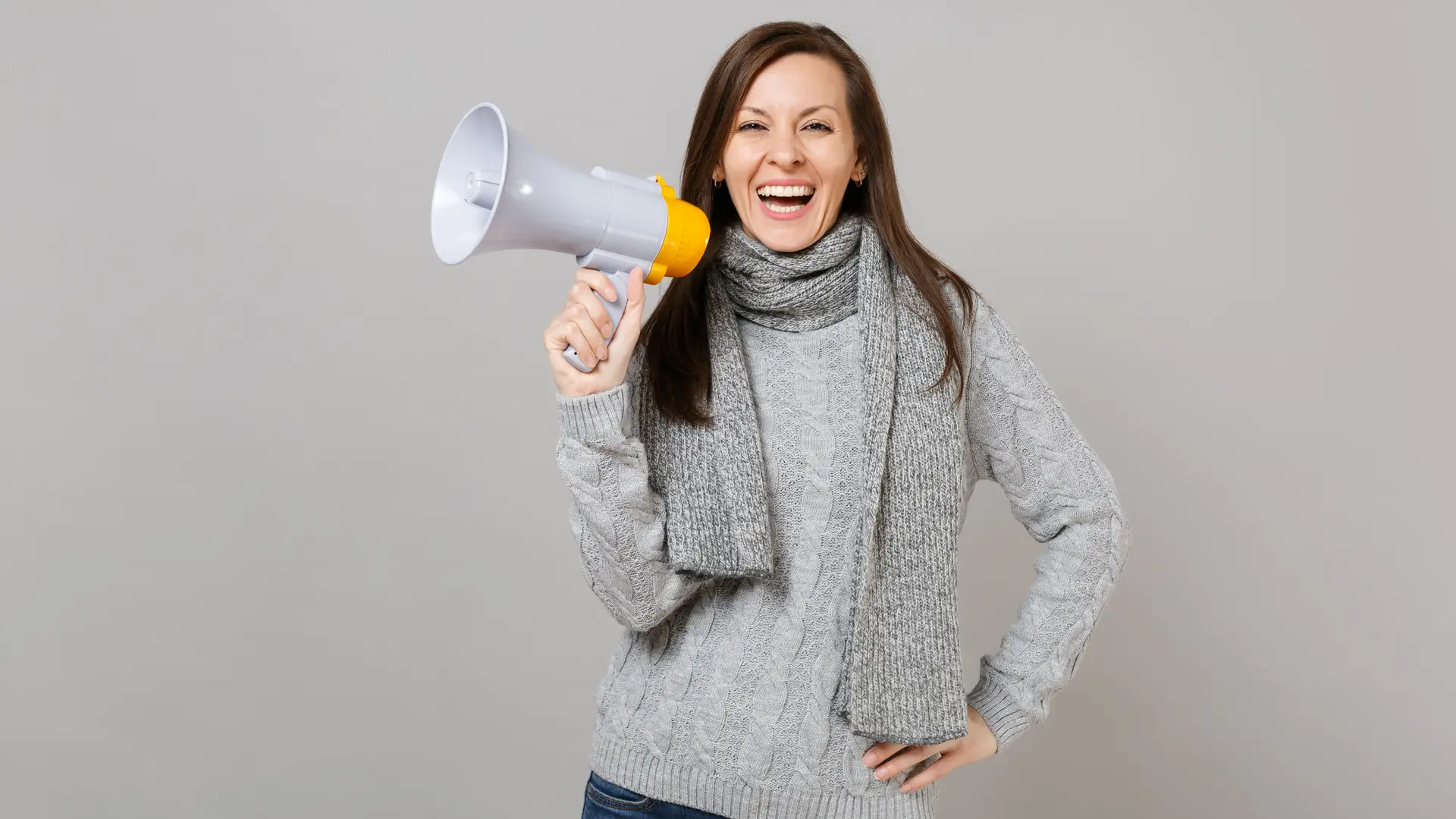 Mujer sostiene un megáfono mientras sonrie representando las opiniones de los usuarios de embou Mujer sostiene un megáfono mientras sonrie representando las opiniones de los usuarios de embou