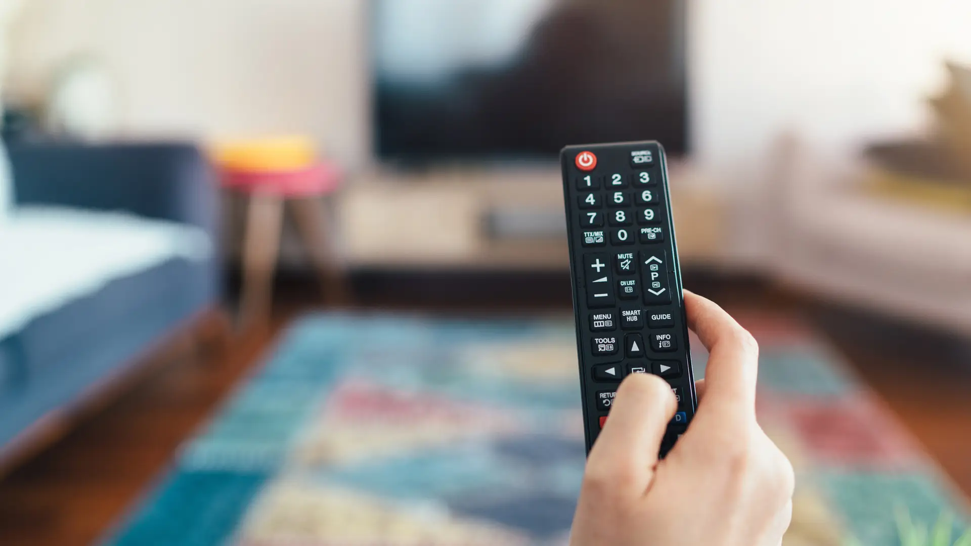 Joven con mando a distancia cambiando de canal en su decodificador 4k