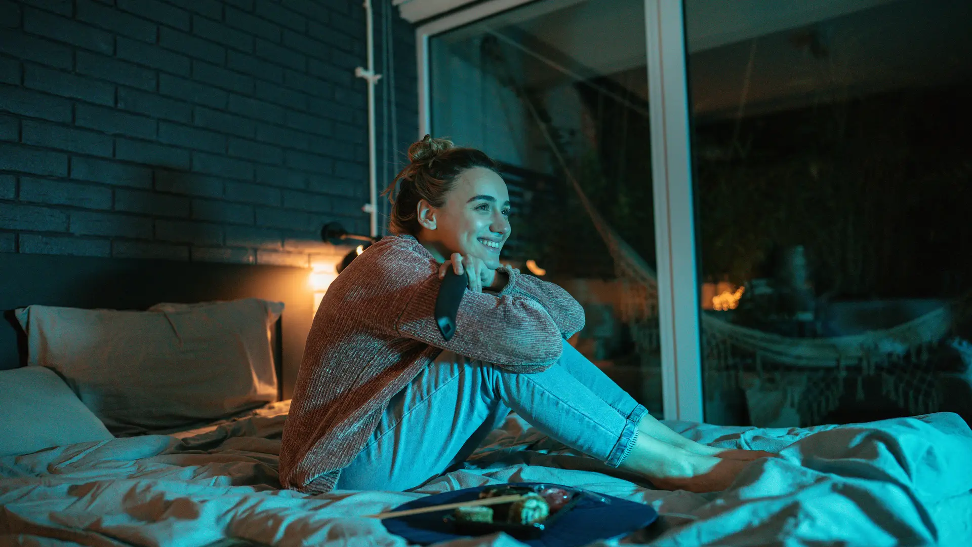 Mujer viendo televisión en dormitorio simboliza segunda tv
