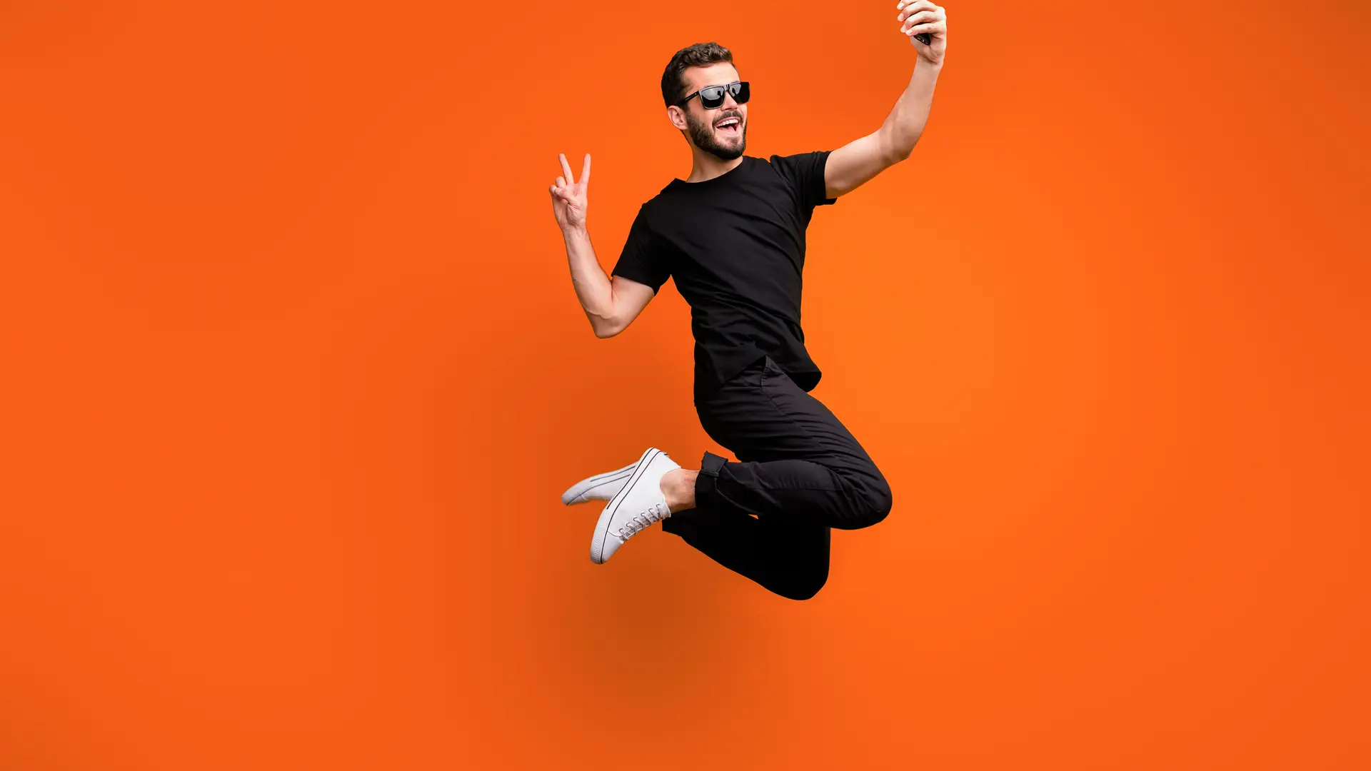 Joven con smartphone saltando representa portabilidad