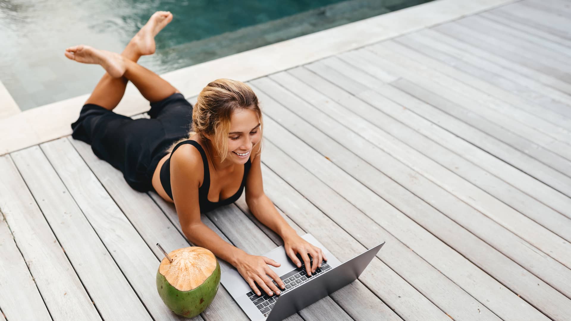 Mujer trabajando con laptop junto a la piscina con tarifa internet wimax