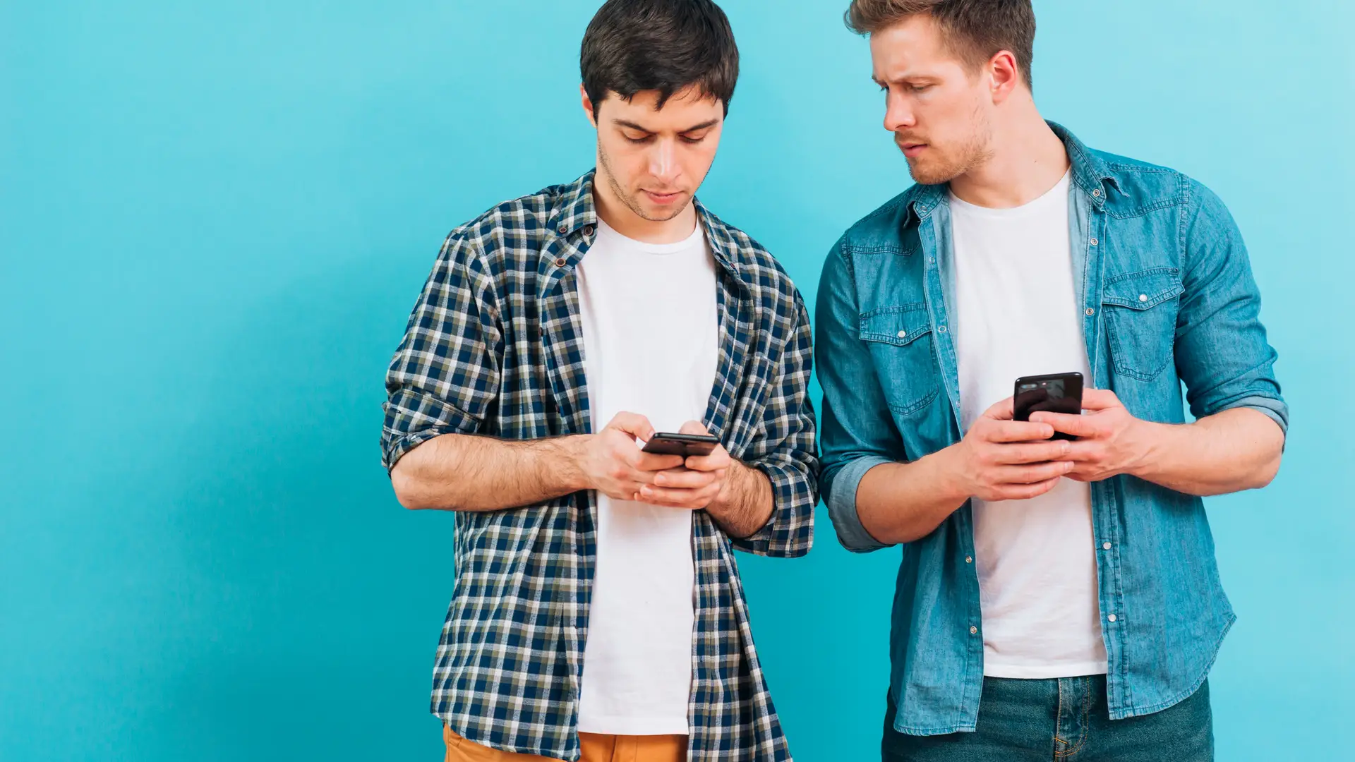 Pareja de chicos siguiendo los pasos necesarios en sus móviles para activar el APN de Excom Pareja de chicos siguiendo los pasos necesarios en sus móviles para activar el APN de Excom