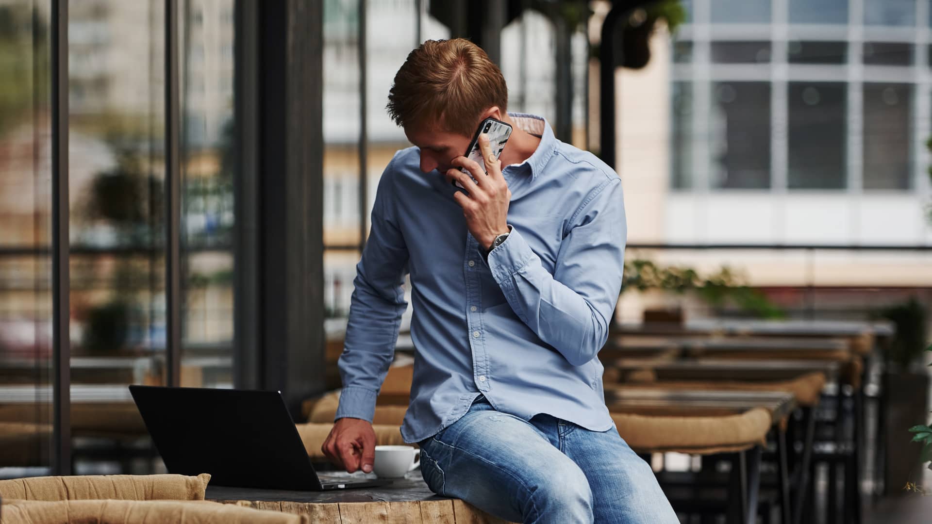 Hombre consulta en su portatil las tarifas de internet disponibles de excom mientras llama para realizar el contrato Hombre consulta en su portatil las tarifas de internet disponibles de excom mientras llama para realizar el contrato