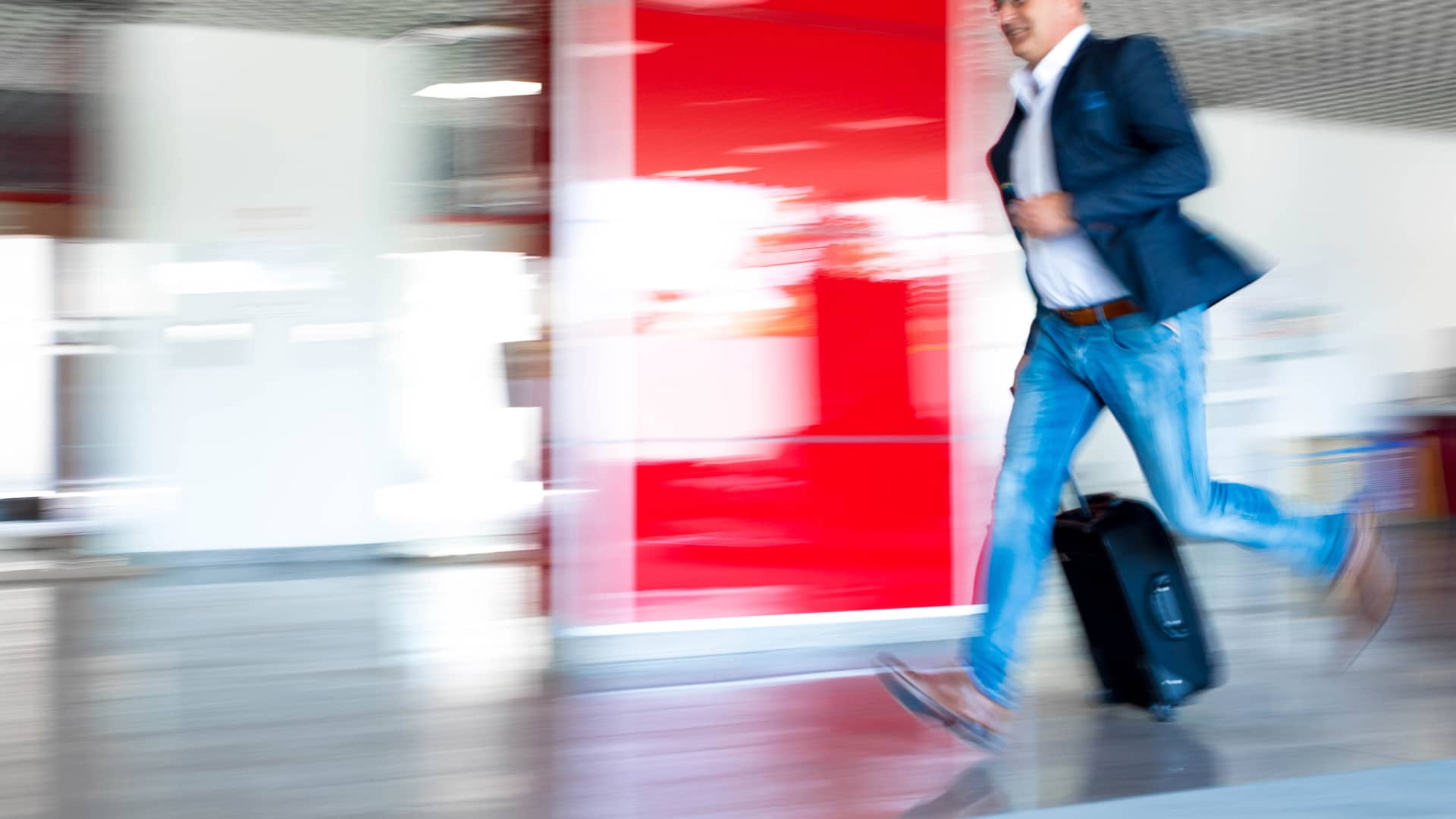 Hombre corriendo por aeropuerto porque pierde su vuelo a otro país simboliza roaming finetwork