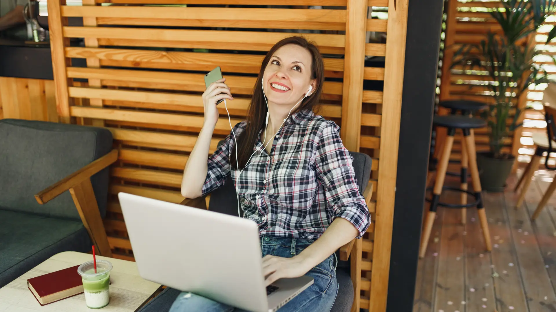 Mujer sonriente en la terraza de un bar mientras habla por teléfono móvil y utiliza su portatil gracias a los bonos de jazztel Mujer sonriente en la terraza de un bar mientras habla por teléfono móvil y utiliza su portatil gracias a los bonos de jazztel