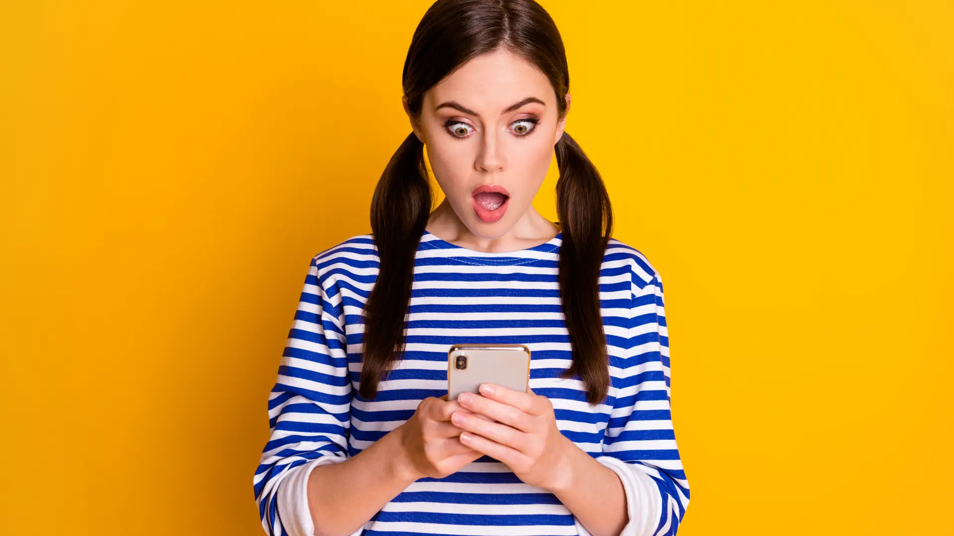 Mujer con cara de susto mira a su móvil jazztel al darse cuenta de que ha introducido mal el PIN y necesitará el PUK Mujer con cara de susto mira a su móvil jazztel al darse cuenta de que ha introducido mal el PIN y necesitará el PUK