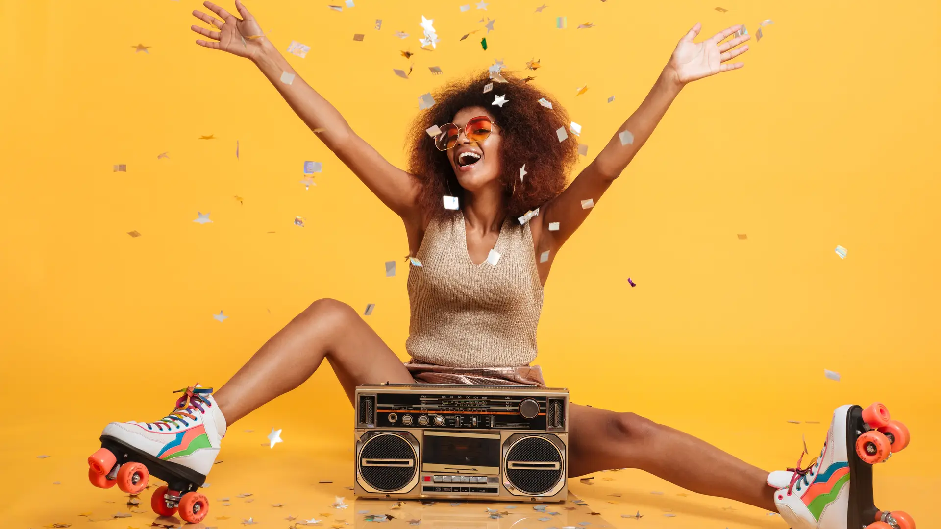 Mujer sentada en el suelo con patines roller y radio cassette celebra con confeti la liberación de su móvil jazztel Mujer sentada en el suelo con patines roller y radio cassette celebra con confeti la liberación de su móvil jazztel