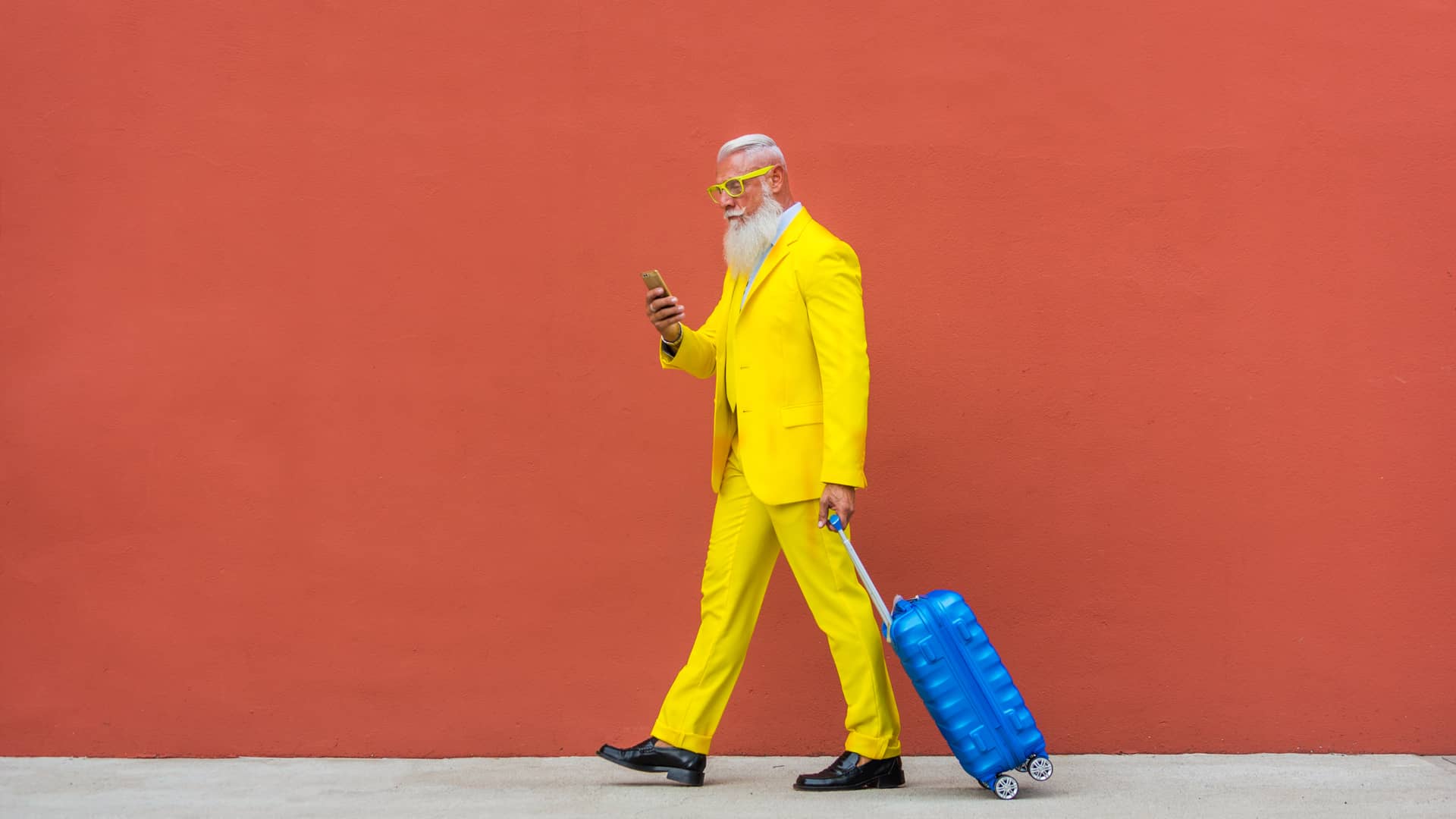 Hombre mayor con traje y gafas amarillas, lleva una maleta y un móvil, simulando su portabilidad a Jazztel