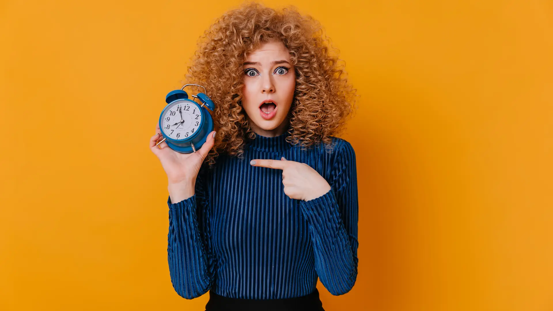 Joven con el pelo rizado señala a un reloj con cara de sorpresa representando la permanencia que queda de su contrato jazztel Joven con el pelo rizado señala a un reloj con cara de sorpresa representando la permanencia que queda de su contrato jazztel