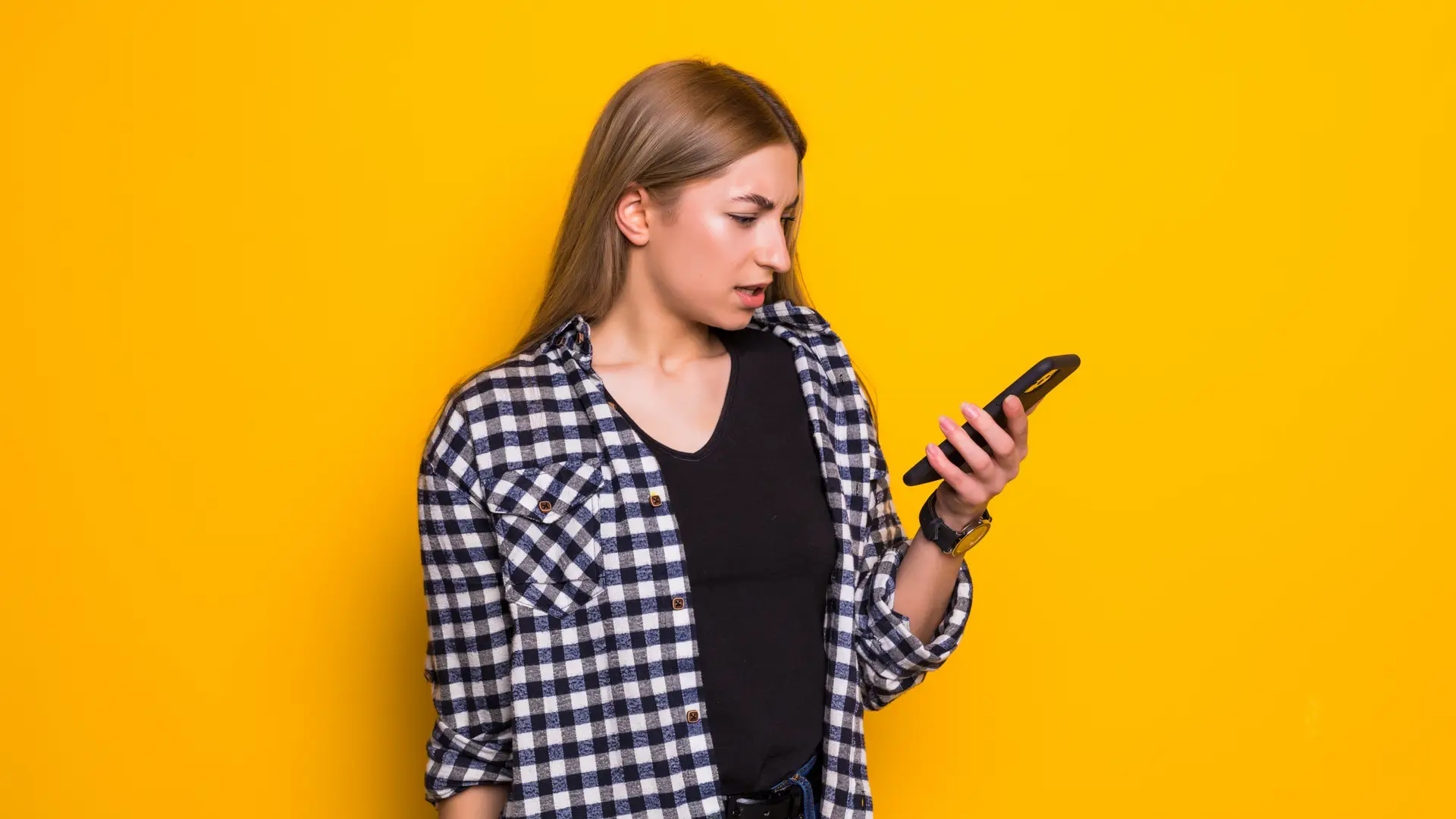 Joven mira perpleja su teléfono movil llamaya porque necesitará buscar su código PUK para poder iniciarle correctamente Joven mira perpleja su teléfono movil llamaya porque necesitará buscar su código PUK para poder iniciarle correctamente