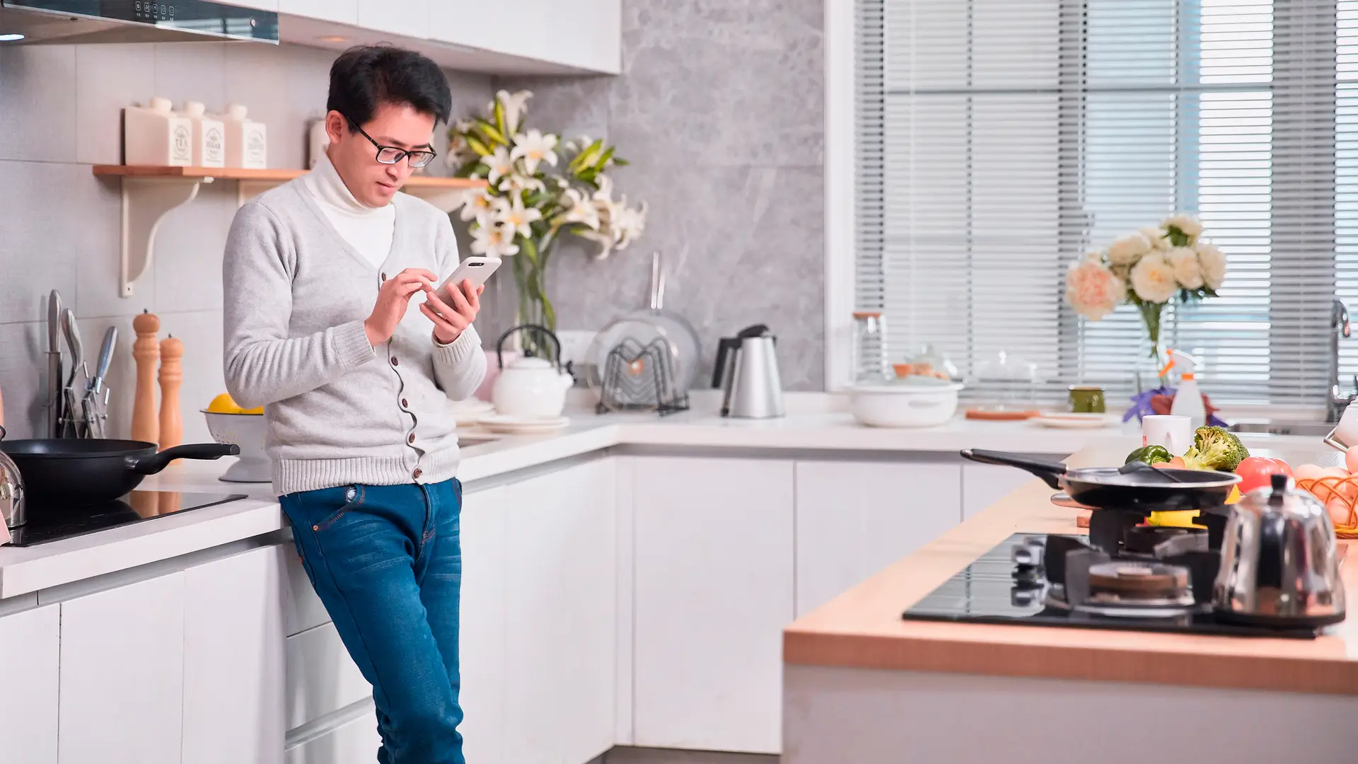 Hombre consultando el saldo de su móvil mientras prepara la comida Hombre consultando el saldo de su móvil mientras prepara la comida