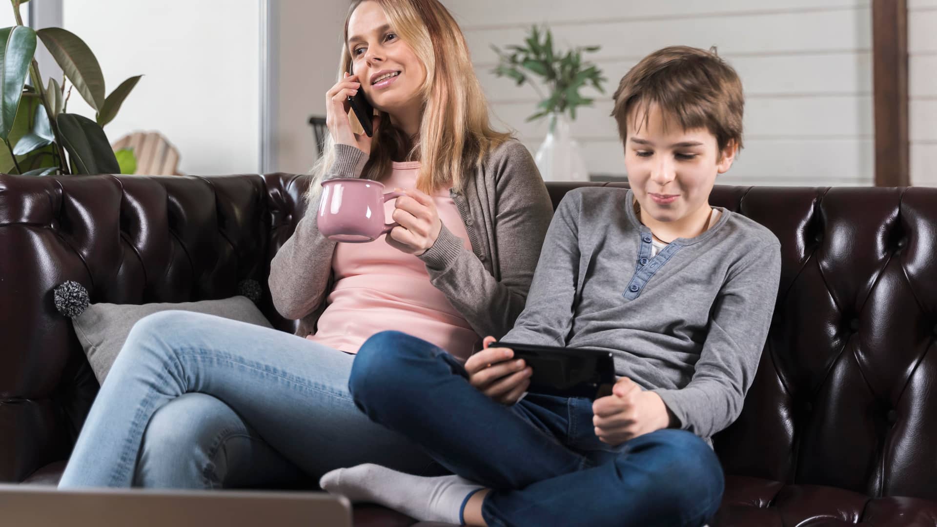 Madre e hijo adolescente utilizan sus teléfonos moviles mientras se plantean cuando realizar el cambio de titular del móvil del pequeño