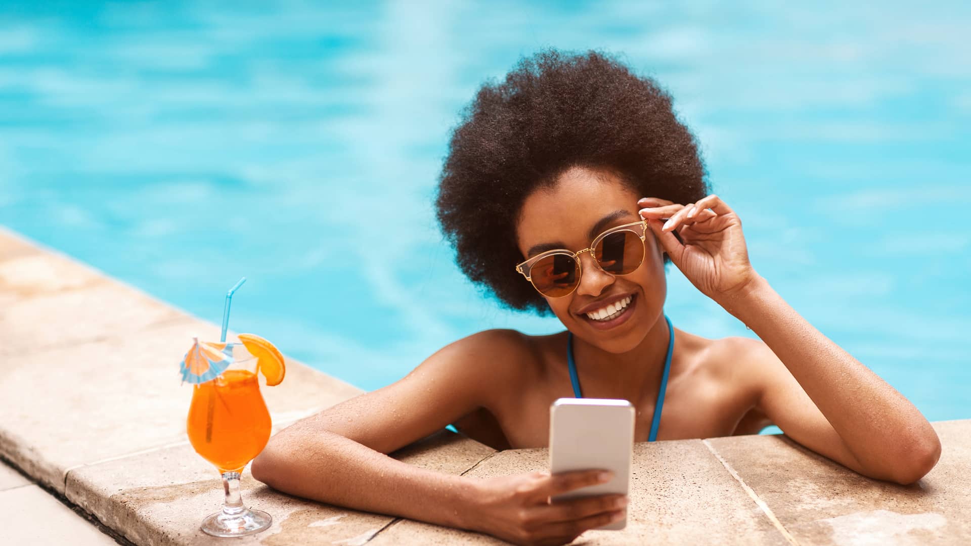 Mujer en el borde de la piscina disfrutando con su móvil de los 60gb gratis de lowi