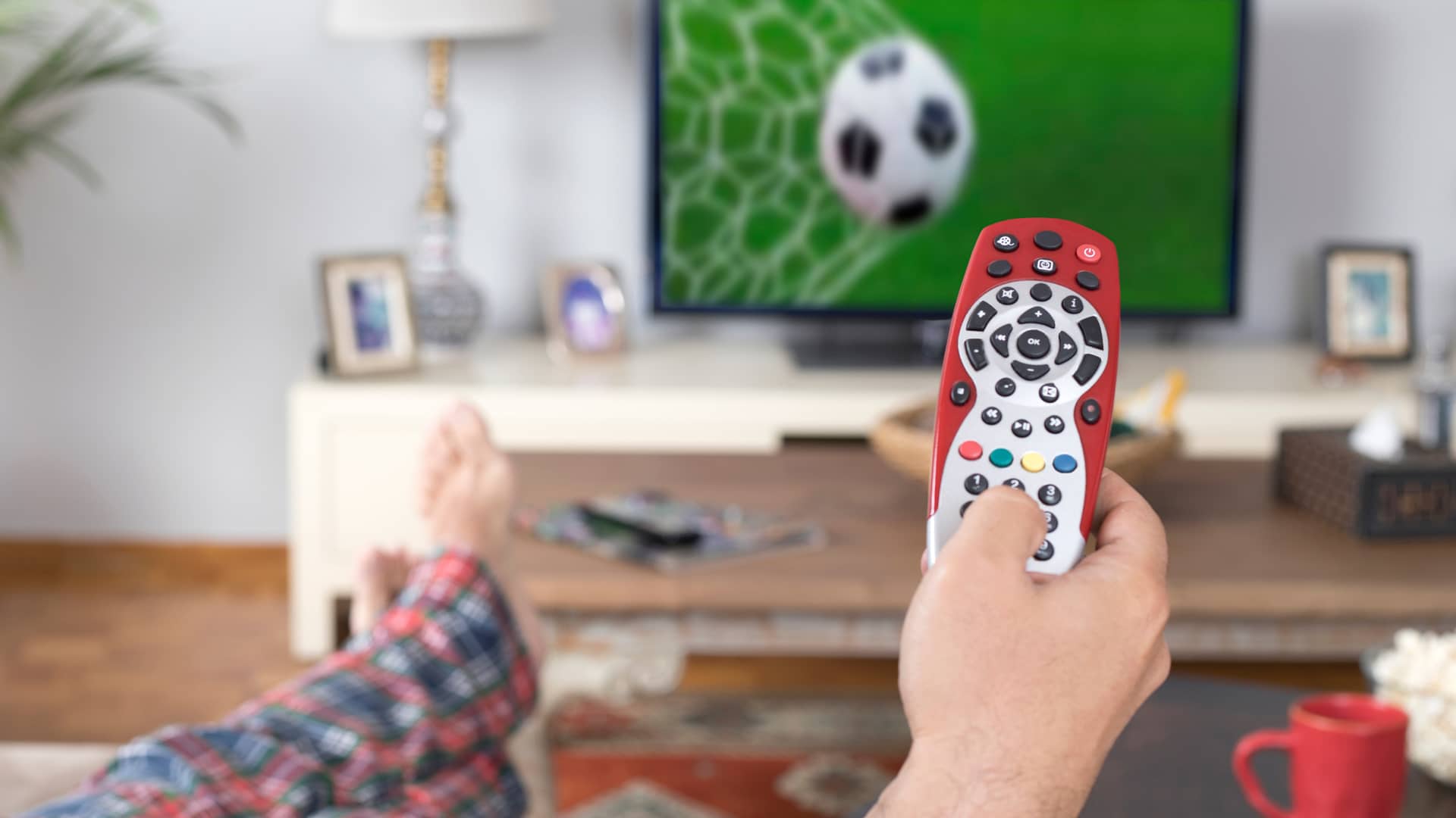 Hombre con mando te tv viendo partido de fútbol en la televisión representa fibra fútbol