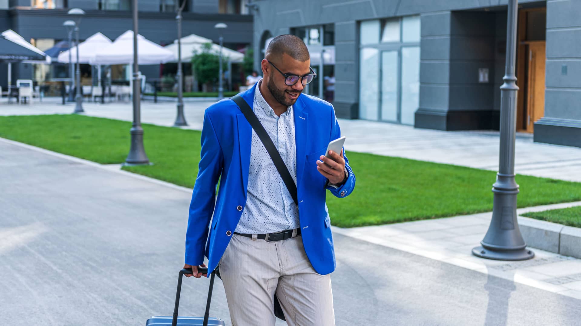 Hombre viendo su smartphone mientras lleva se dirije al aeropuerto con su maleta representa llamadas internacionales lowi